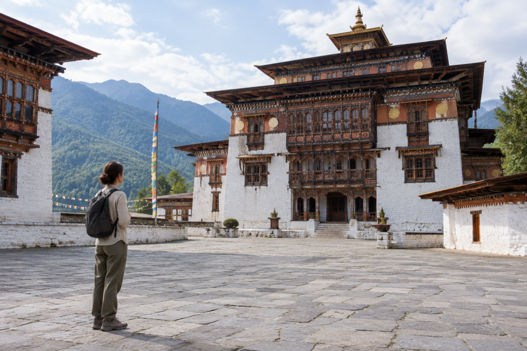 Traveler in a collared long-sleeve shirt and long trousers standing in a whitewashed dzong courtyard in Bhutan
